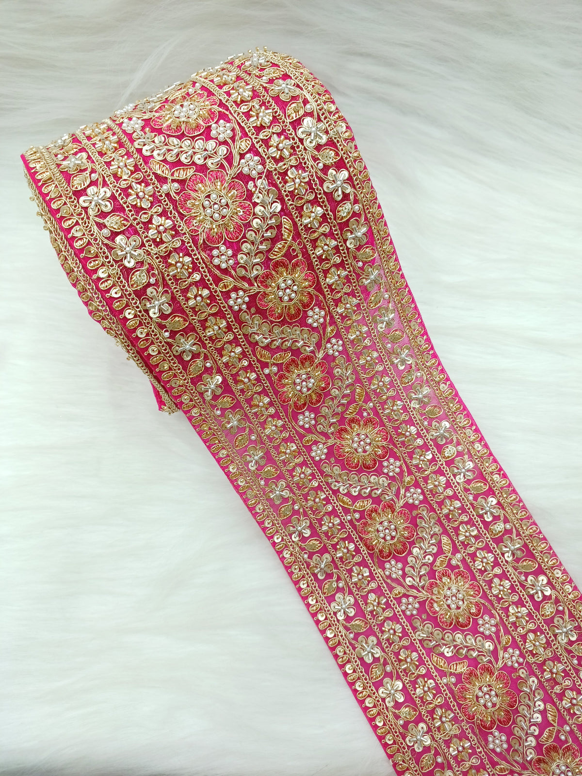 Rani pink net lace with intricate cutdana and moti handwork, featuring detailed embroidery and delicate floral patterns.