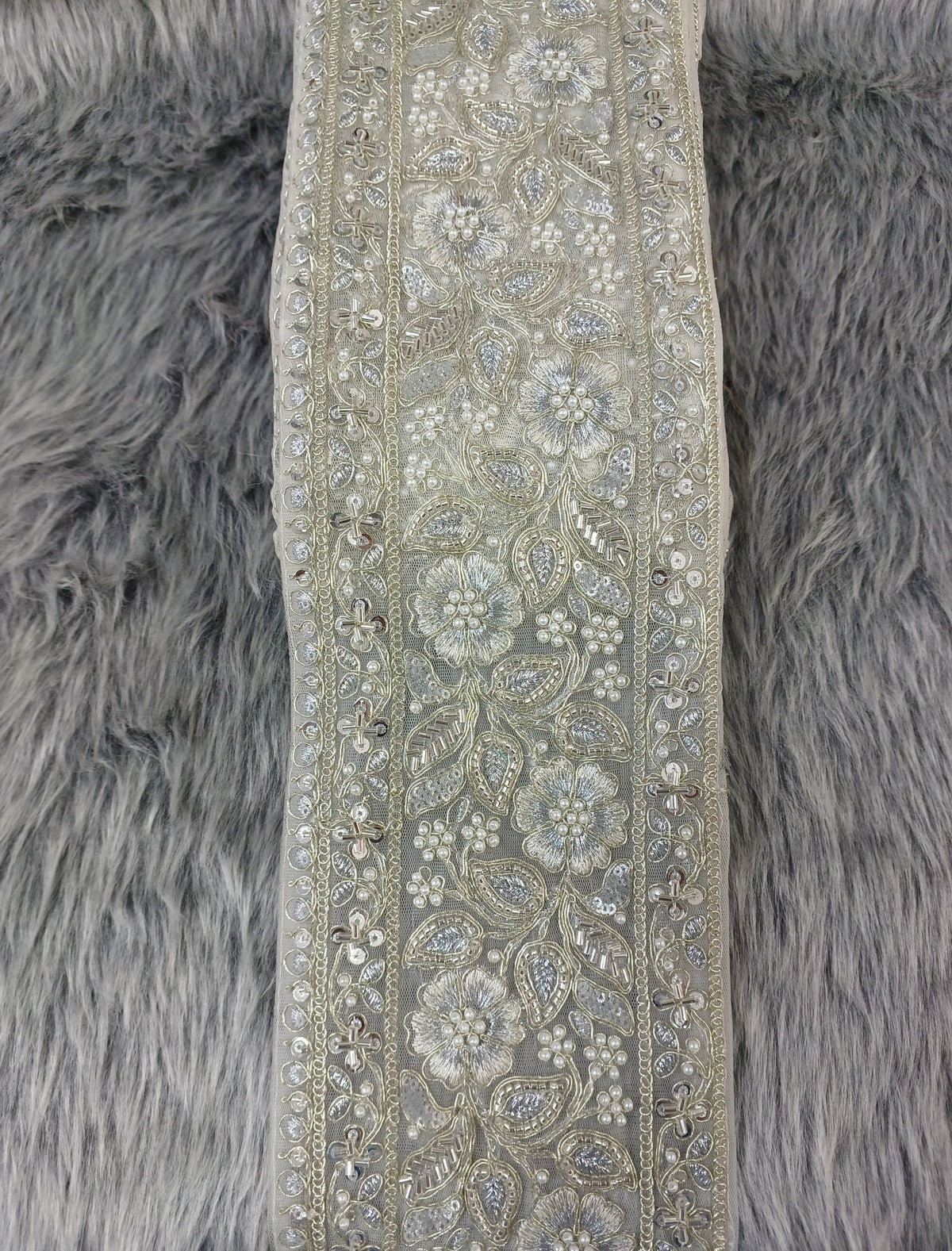 Silver lace with intricate cutdana and moti handwork, featuring detailed embroidery and shimmering embellishments, by Lace Hut.