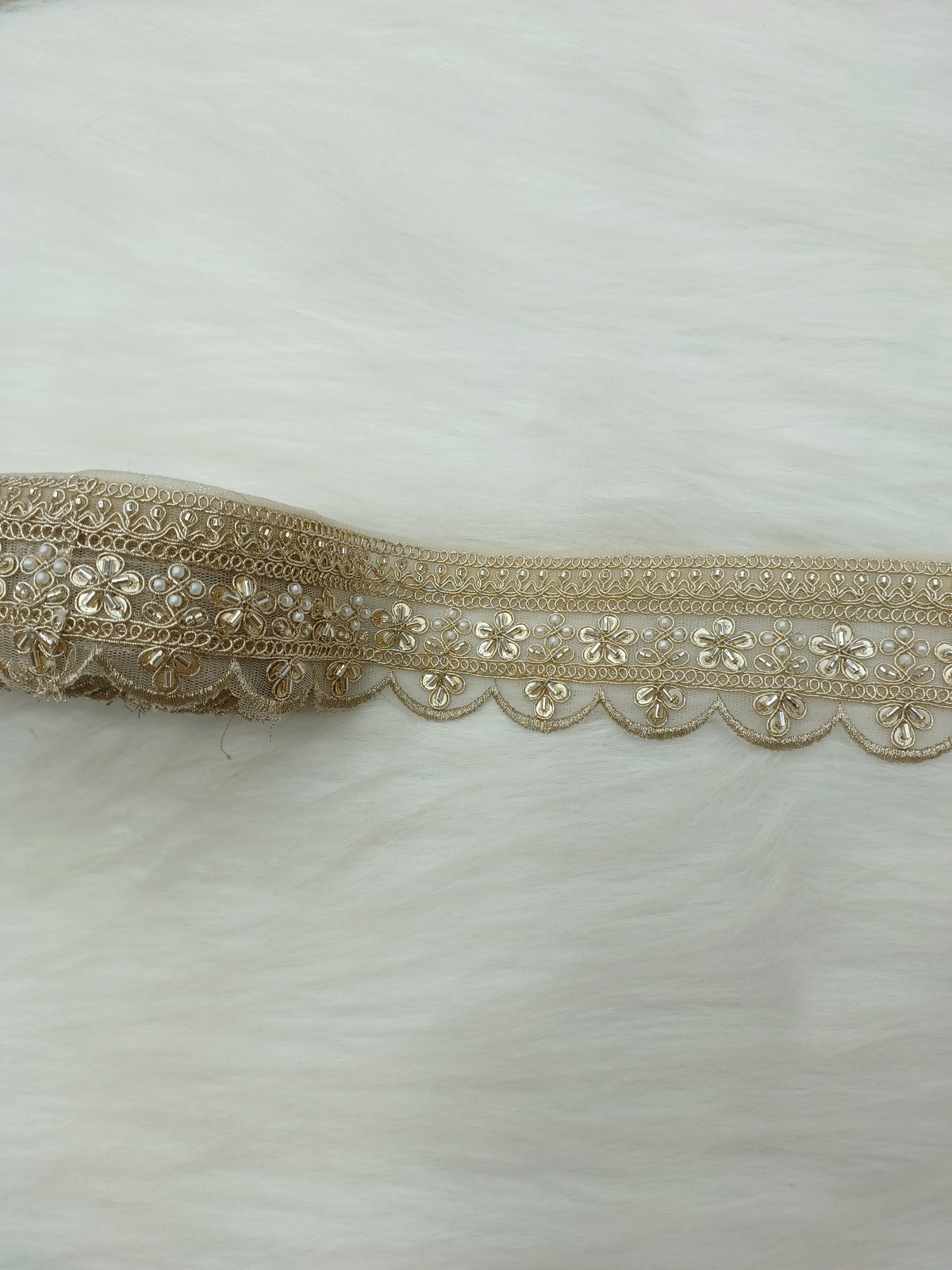 Gold scallop water lace with cutdana and moti handwork, showcasing intricate embroidery and scalloped edges.