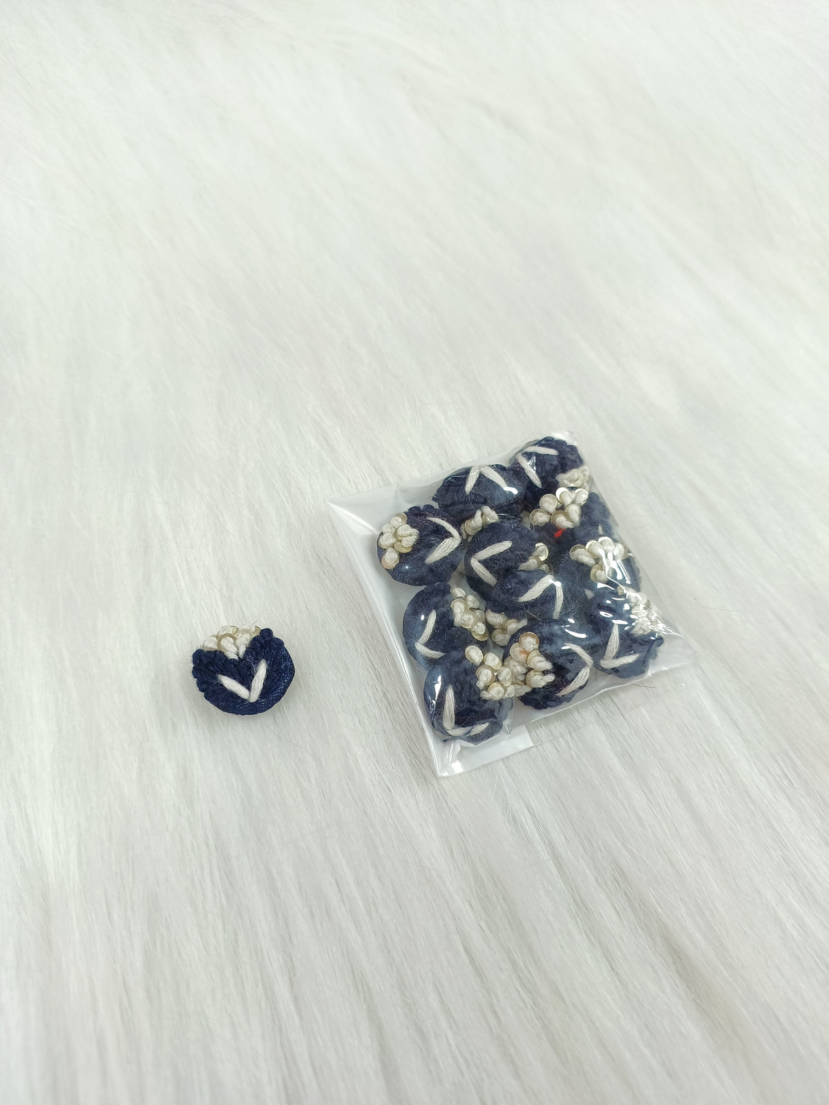 Blue crochet handwork nevi button from Lace Hut with a lacy design and a single button detail.