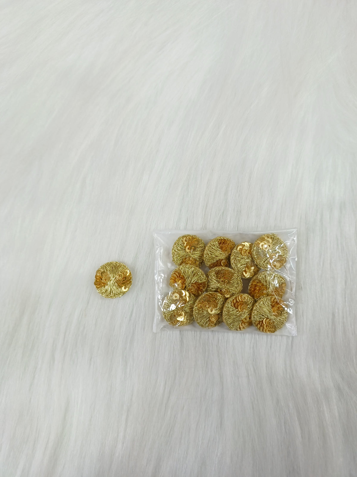 Bright golden Jari and sequence button from Lace Hut, showcasing intricate design and shiny finish on a neutral background.