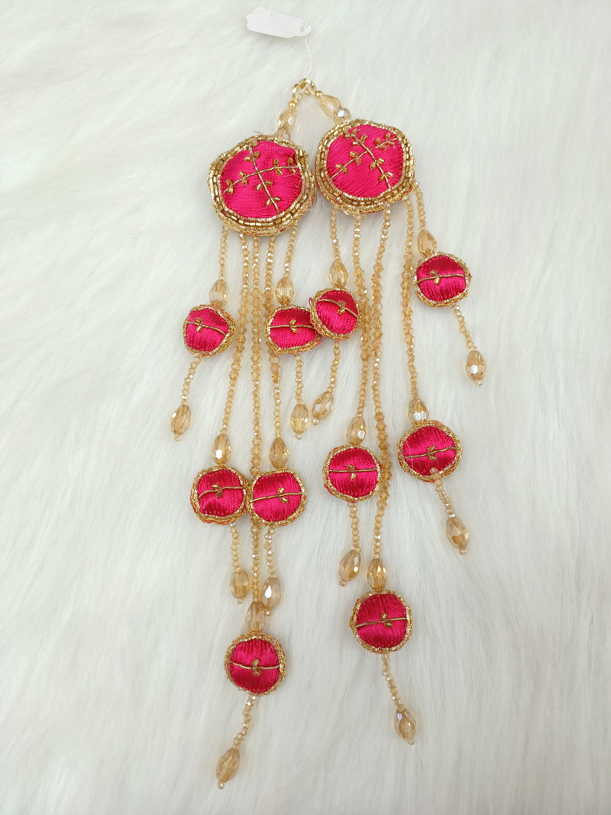 Reddish pink lehenga with Zardosi cutdana and crystal handwork, featuring decorative latkan embellishments.