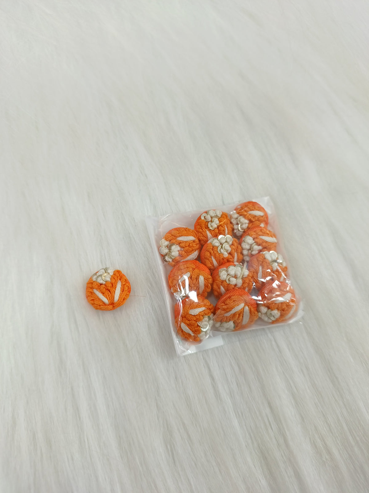 Orange crochet handwork button from Lace Hut featuring intricate textured design and a single functional button.