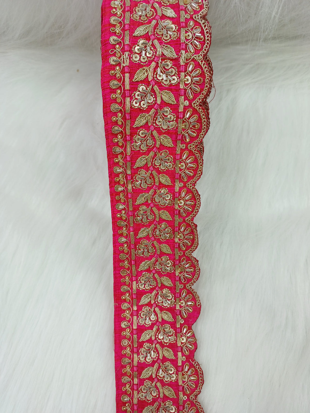 Reddish pink lace with intricate cutdana and jari handwork, showcasing detailed embroidery and delicate design.