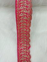 Reddish pink lace with intricate cutdana and jari handwork, showcasing detailed embroidery and delicate design.